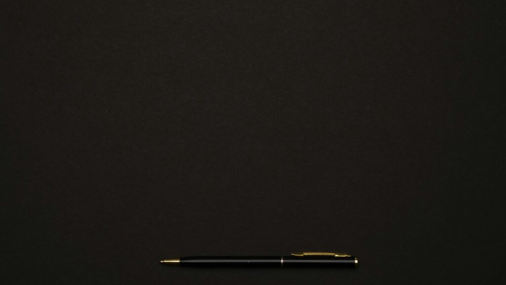 A sleek black pen placed on a minimalist dark background, perfect for professional presentations.